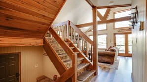 Una escalera de madera que lleva a una sala de estar con un sofá y un cartel que dice 'Welcome to the cabin'.