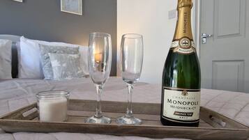 Een fles champagne, twee glazen en een kaars op een dienblad in een slaapkamer.