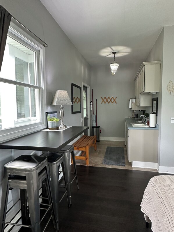 A compact kitchen with a dining area, a wooden bench, and a small table with bar stools. - Enjoy your stay at our in-law suite, just minutes away from Bellaire MI. (Bellaire)