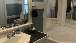 Un bagno con un lavandino bianco, uno specchio grande e una vasca da bagno.