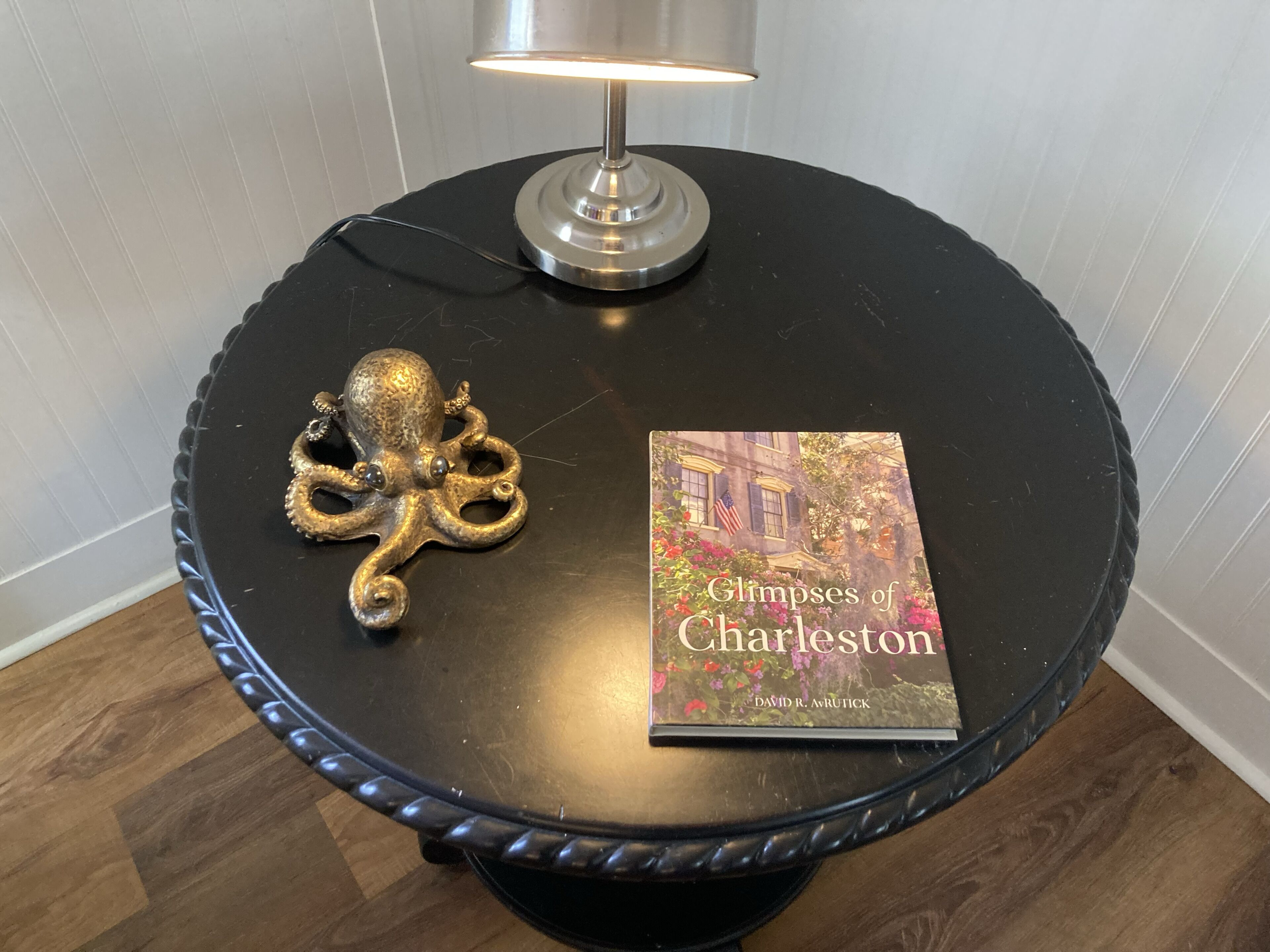 A round table with a book titled "Glimpses of Charleston" and a decorative octopus ornament.