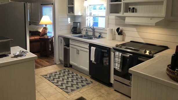 Una cucina moderna con mobili bianchi, forno integrato, lavastoviglie e macchina per il caffè.