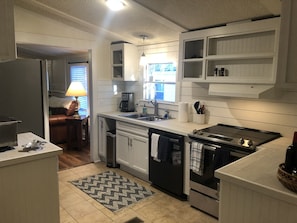 A modern kitchen with white cabinetry, a built-in oven, a dishwasher, and a coffee maker. - Historic Beaufort, South Carolina Near Hilton Head, SC, New Renovation, Sleeps 8 (Beaufort)
