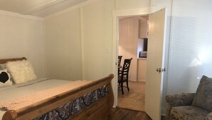 Una camera da letto con un letto di legno, un piccolo divano e una porta che dà su una cucina.