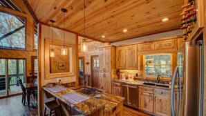 A spacious kitchen with wooden cabinets, a granite countertop, and a stainless steel refrigerator.