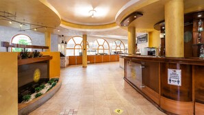 Un vestíbulo amplio con una recepción, un gran ventanal de arco y una decoración floral.