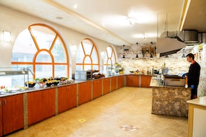 Una cocina amplia con grandes ventanales de arco, una pared de acento de piedra y una variedad de electrodomésticos de cocina.