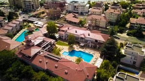Vista aérea de una zona residencial costera con piscina, varios edificios y una playa al fondo.