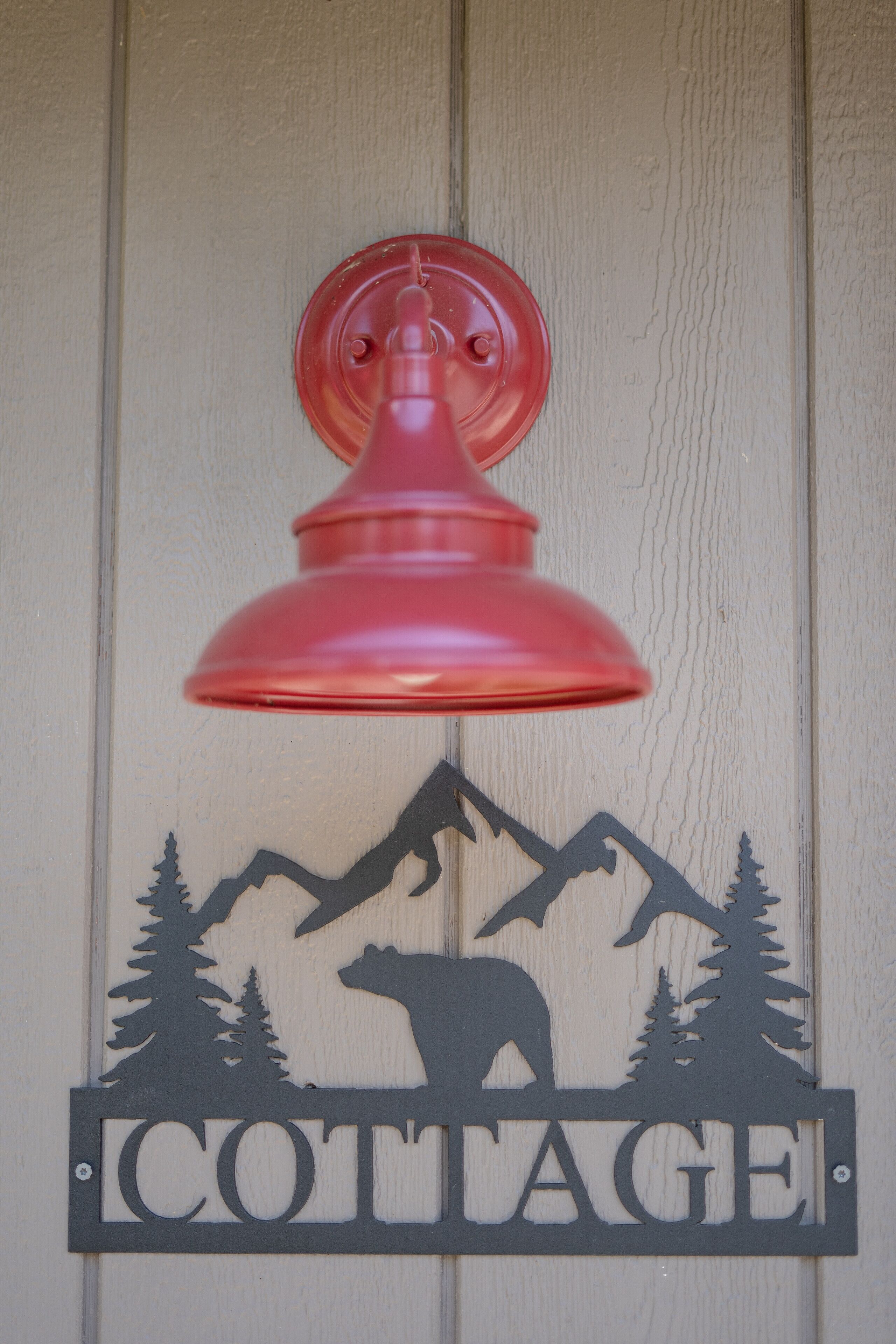 Eine an der Wand befestigte Schild mit einer Bärensilhouette und Bergesignatur, beschriftet mit „COTTAGE“.