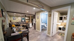 A dining area with a table set for four, a kitchen in the background, and a hallway leading to a bathroom. - Roscoe Cottage Pet Friendly  (Roscoe)