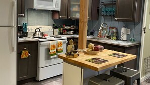 A kitchen with a central island, a stove, a refrigerator, and cabinets. - Roscoe Cottage Pet Friendly  (Roscoe)