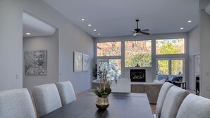 Un comedor moderno con una mesa de madera oscura, sillas tapizadas en gris y un jarrón con orquídeas blancas.