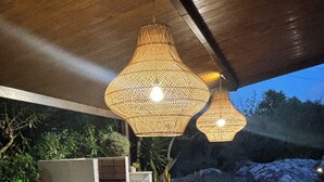 An outdoor seating area with wicker furniture, a table with a plate and a cup, and two large wicker pendant lights. - QUIET FINCA CAN XAVI (Alcudia)