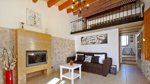 A spacious living room with a stone fireplace, a sofa, and a small table. - QUIET FINCA CAN XAVI (Alcudia)
