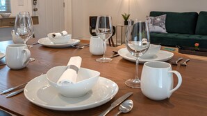 A dining table set with white plates, bowls, and cutlery, with empty wine glasses and a white pitcher. - Close to it all!  Long Beach 5bed/4bath (Long Beach)