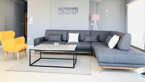 A modern living room with a grey sectional sofa, a yellow armchair, and a coffee table. - Downtown Apartments (Pristina)