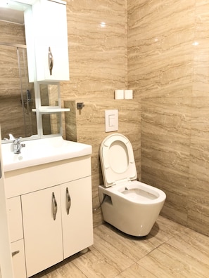 A modern bathroom with a white sink, a toilet, and a mirror above the sink. - Downtown Apartments (Pristina)
