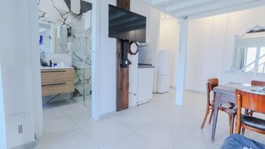 Una cocina moderna con horno integrado, microondas y un televisor de pantalla plana grande montado en la pared.