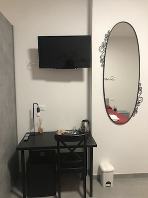 Relax in a cozy space with a flat-screen TV, oval mirror, and comfortable desk area.