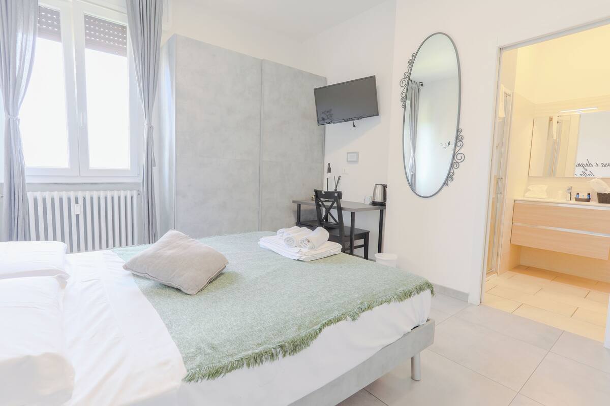 Habitación de hotel con cama, escritorio, silla, televisor y baño.