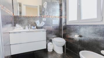 A modern bathroom with a white vanity, a toilet, and a bidet.
