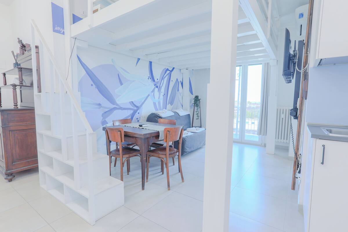 Un interior moderno con comedor, escalera y cocina.