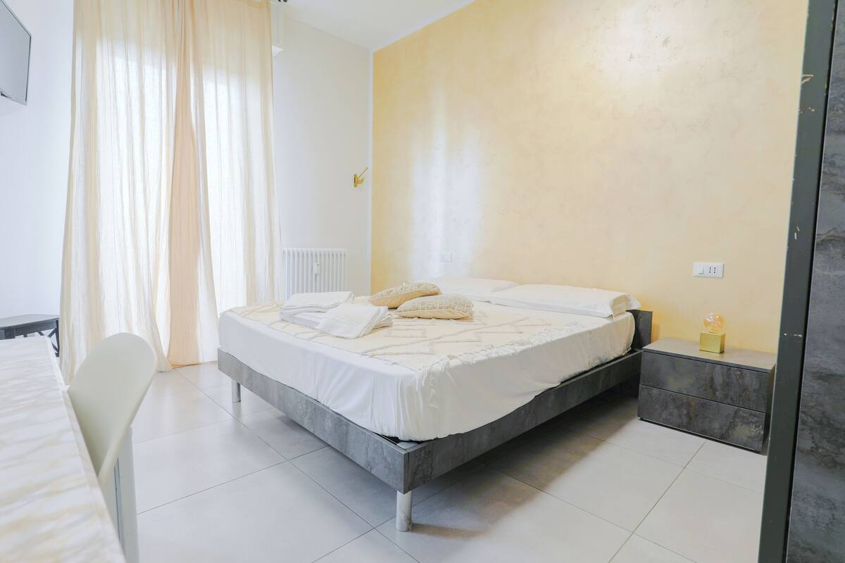 Un dormitorio con cama, mesita de noche y una silla.