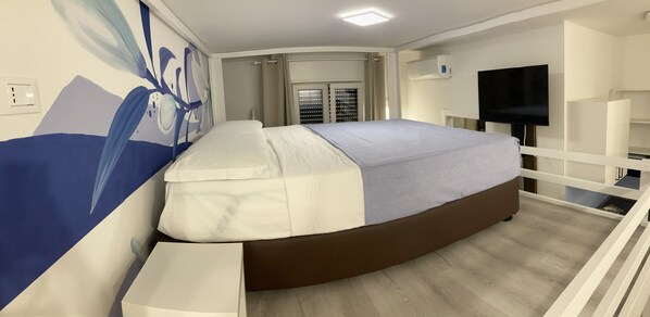 Relax in a stylish room with a curved bed, flat-screen TV, and air conditioning.