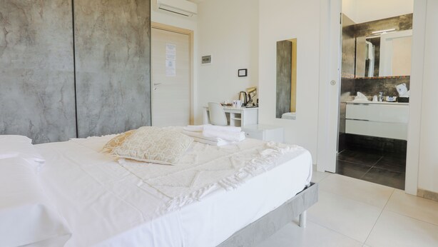 Una habitación de hotel moderna con una cama grande, un escritorio y un baño visible a través de una puerta abierta.