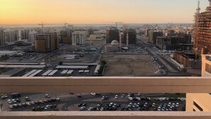 A cityscape with a prominent mosque with two minarets and a dome, surrounded by various buildings and construction sites. - Heartland Hostel (Dubai)