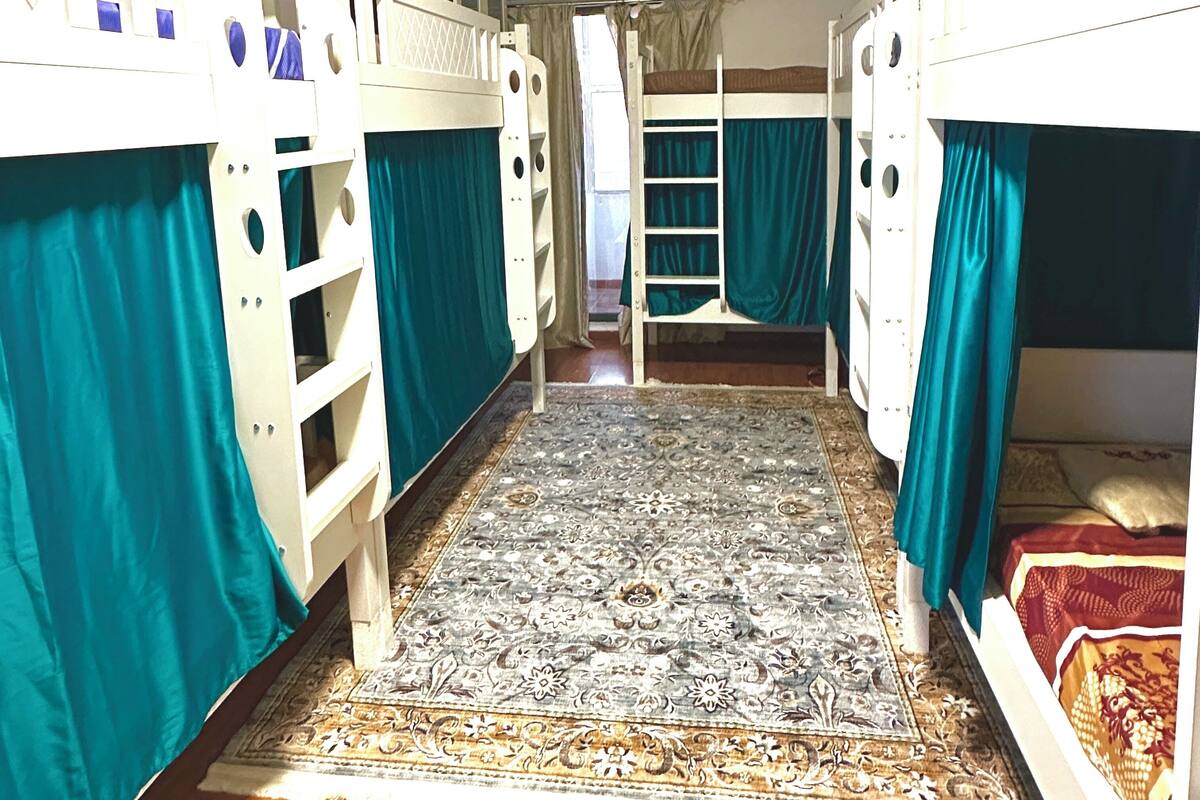 Ein Zimmer mit Etagenbetten, einem gemusterten Teppich und Holzboden.