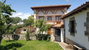 Ein traditionelles, zweistöckiges Haus mit Balkon, Steinmauern und einem Ziegeldach.