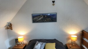 Un dormitorio con una cama, dos mesitas de noche con lámparas, un cuadro en la pared y un detalle decorativo.
