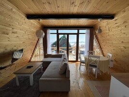 Acogedor dormitorio en ático con interior de madera, un sofá, una mesa de comedor y un televisor.