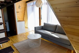 Una sala de estar moderna con un sofá gris, una mesa redonda blanca y piso de madera.