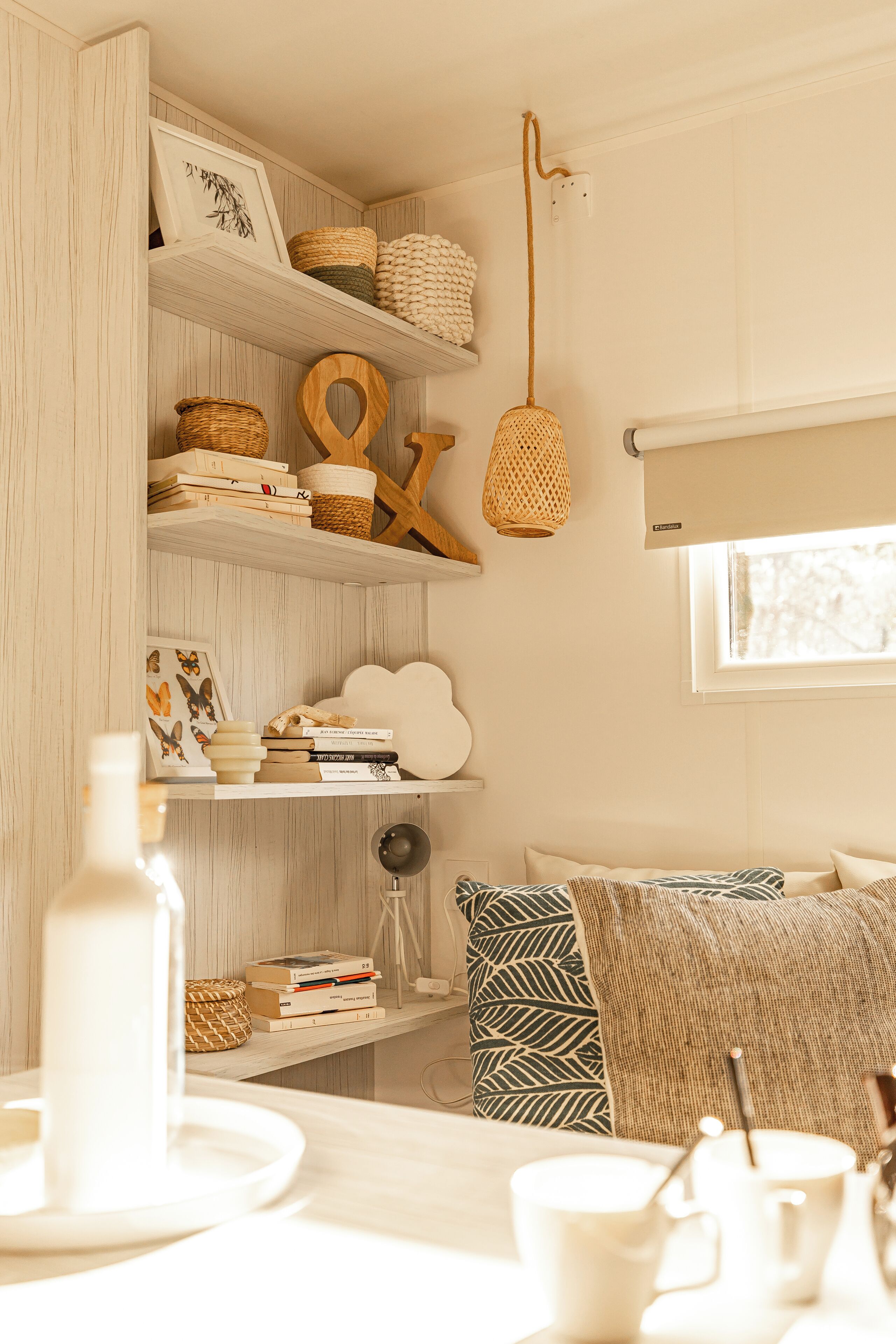 A cozy room with a wooden bookshelf, a hanging light fixture, and a window with a view.