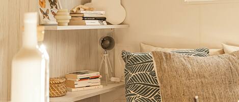A cozy room with a wooden bookshelf, a hanging light fixture, and a window with a view.