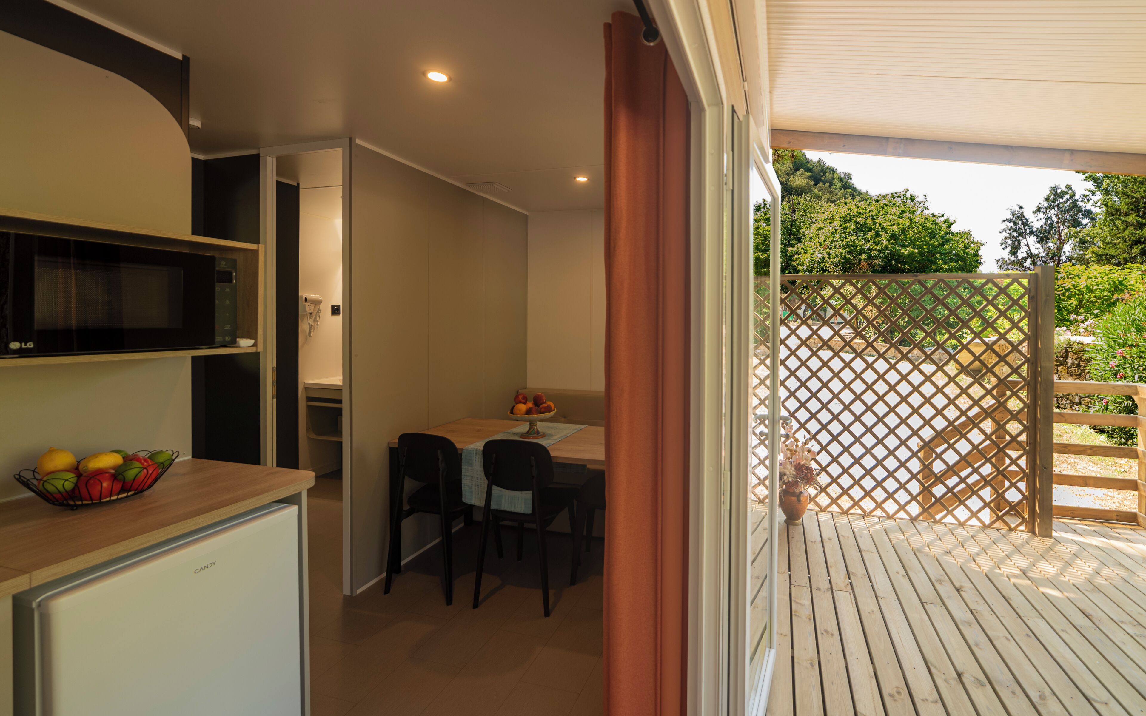 A compact kitchen with a microwave, a fruit bowl, and a refrigerator.