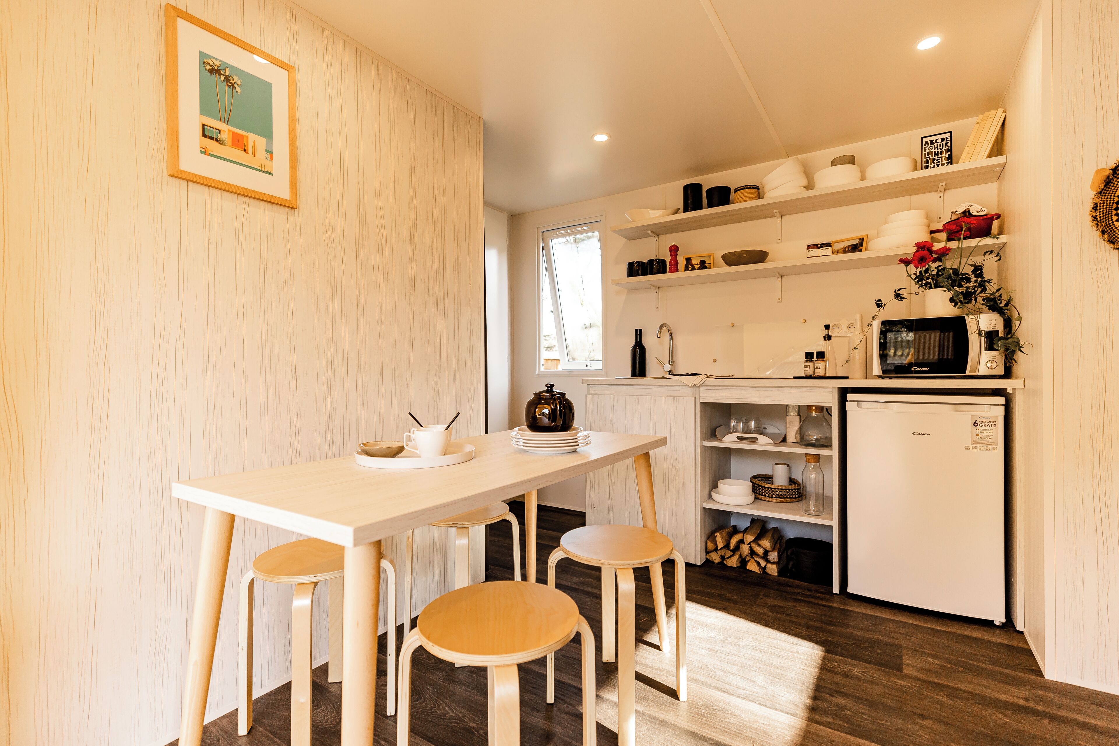 A compact kitchen with wooden stools, a white countertop, and a refrigerator.