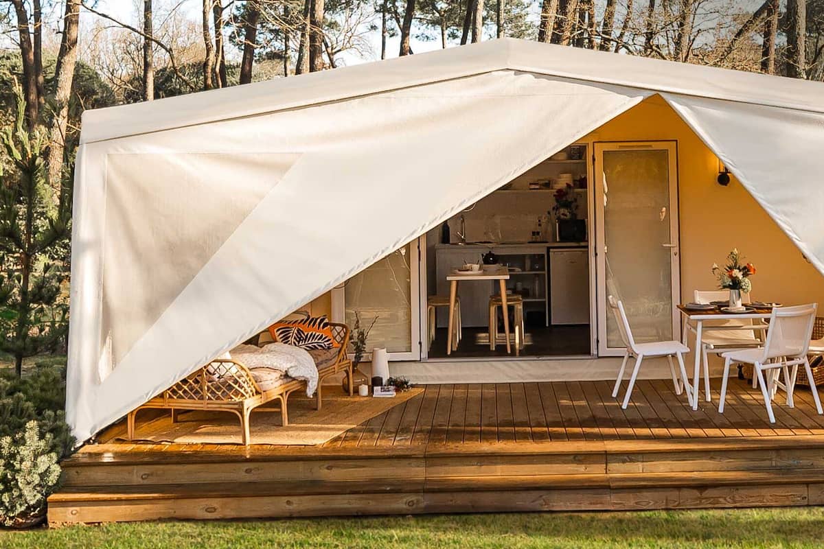 Une tente comprenant un coin cuisine, une table à manger avec des chaises et un lit.