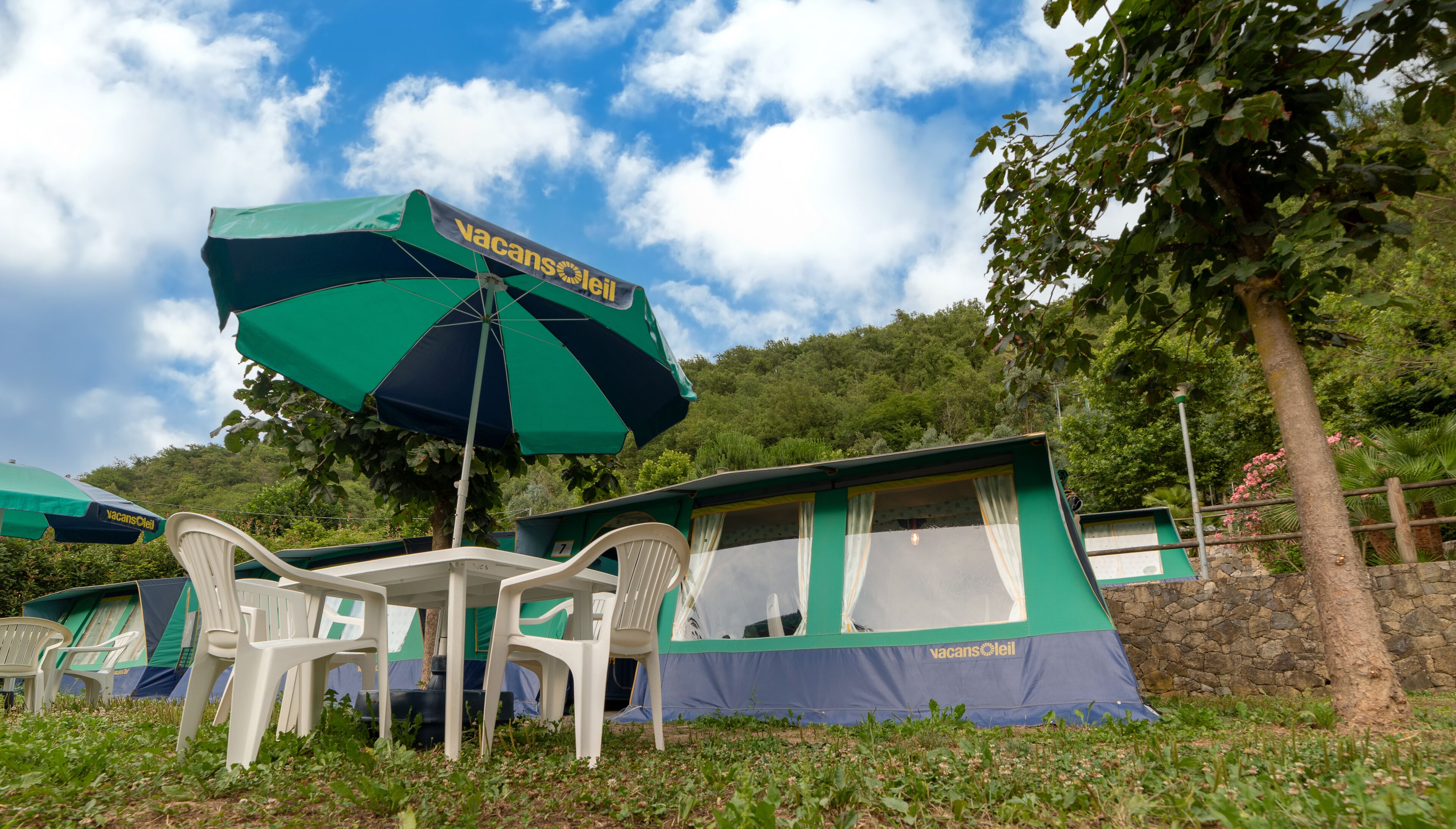 A camping site with tents, chairs, and a large umbrella.