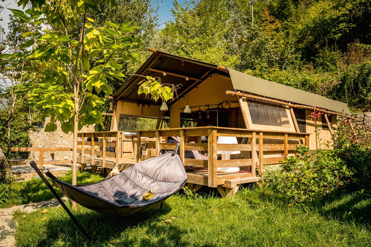 Une cabane en bois rustique dotée d’un porche couvert, d’un hamac et d’un coin repas.