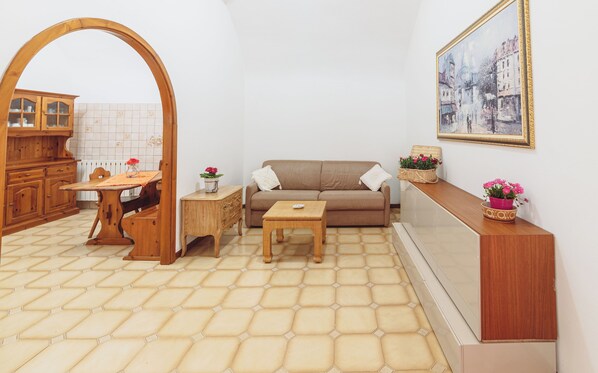 A cozy living room with a wooden dining table, a sofa, and a small wooden side table. - Delle Rose Camping Village (Isolabona)