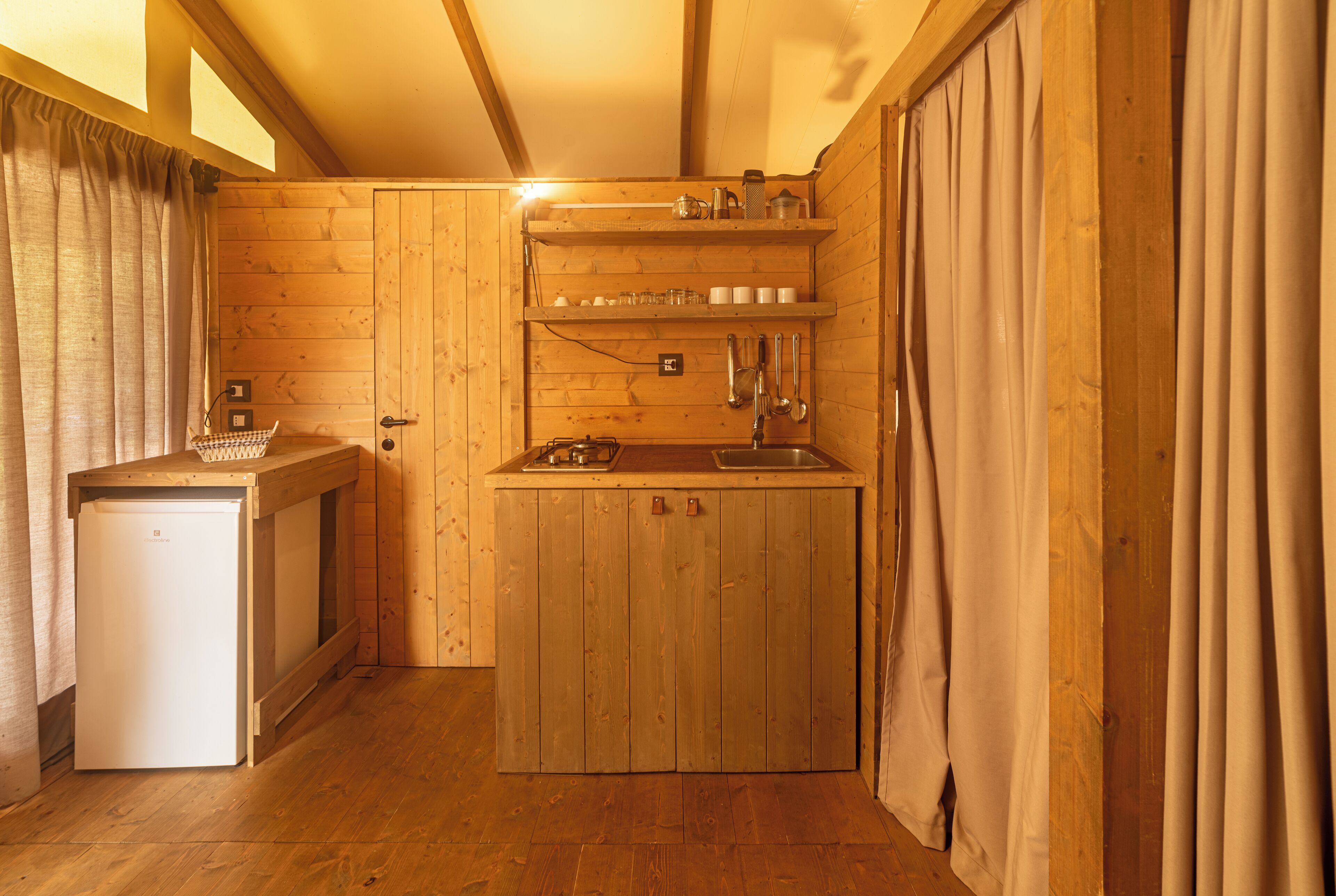 A compact kitchen with wooden cabinets, a sink, and a small refrigerator.