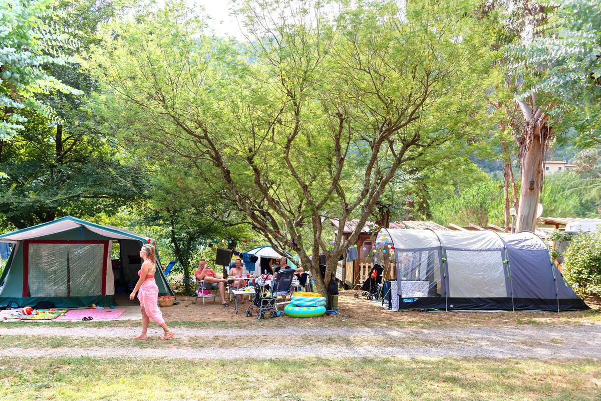 Un terrain de camping avec des tentes, une table et une personne qui marche.