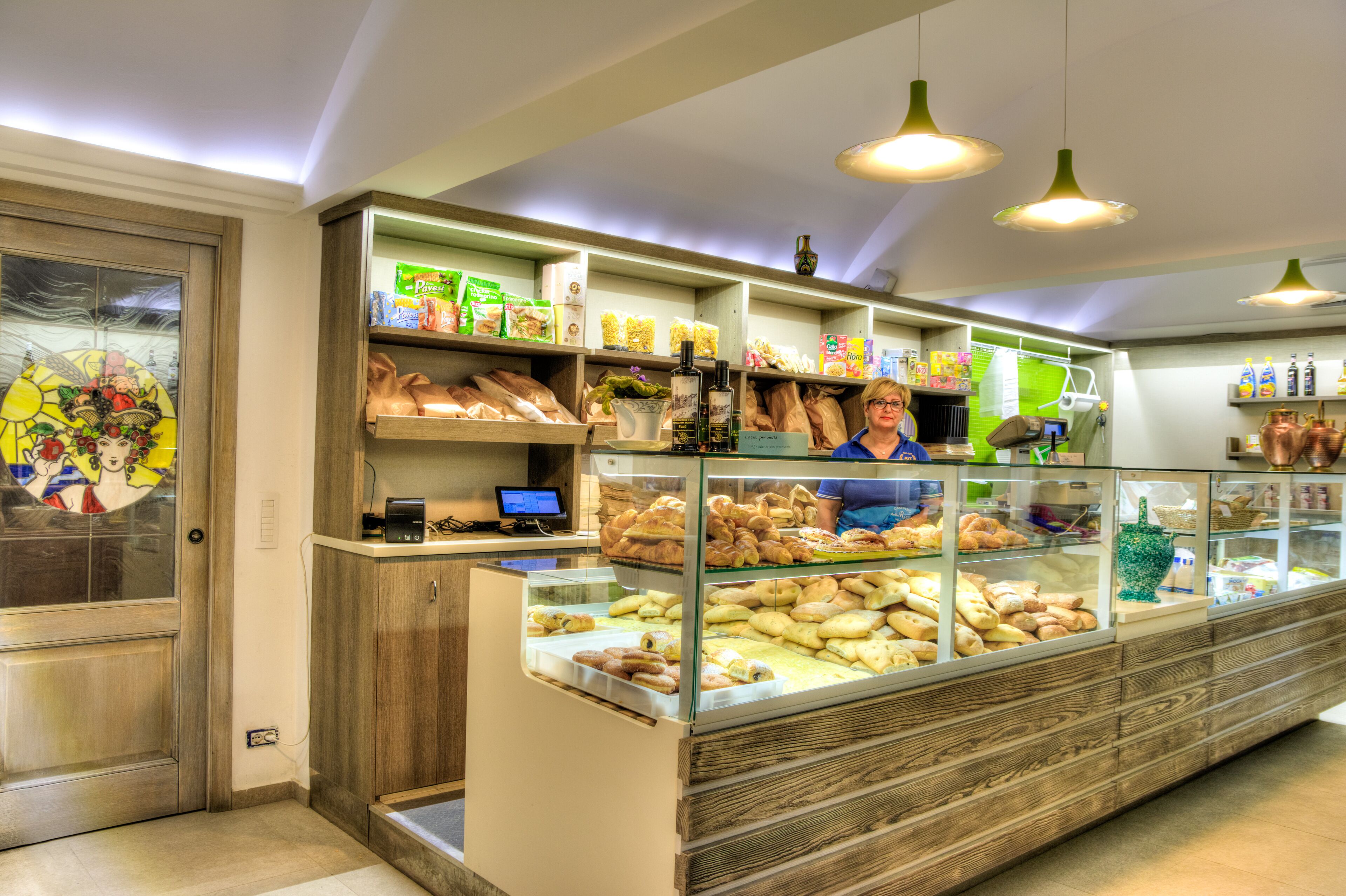 A bakery display case with various baked goods, a digital scale, and a computer monitor.