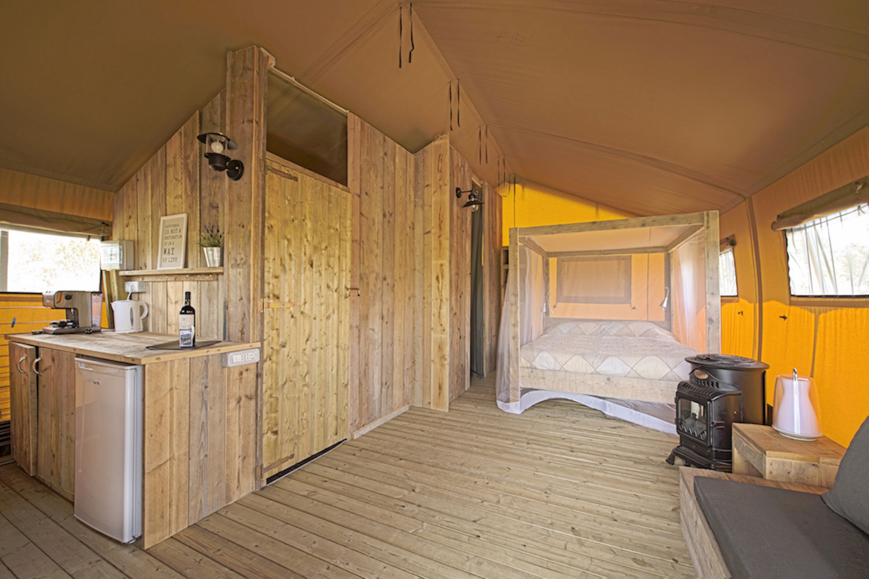 Ein gemütliches Holzhaus mit Küchenzeile, einem Himmelsbett und einem Kaminofen.