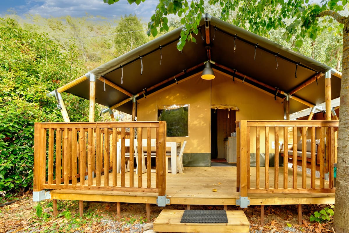 Une cabane en bois avec un porche couvert, une table et des chaises.