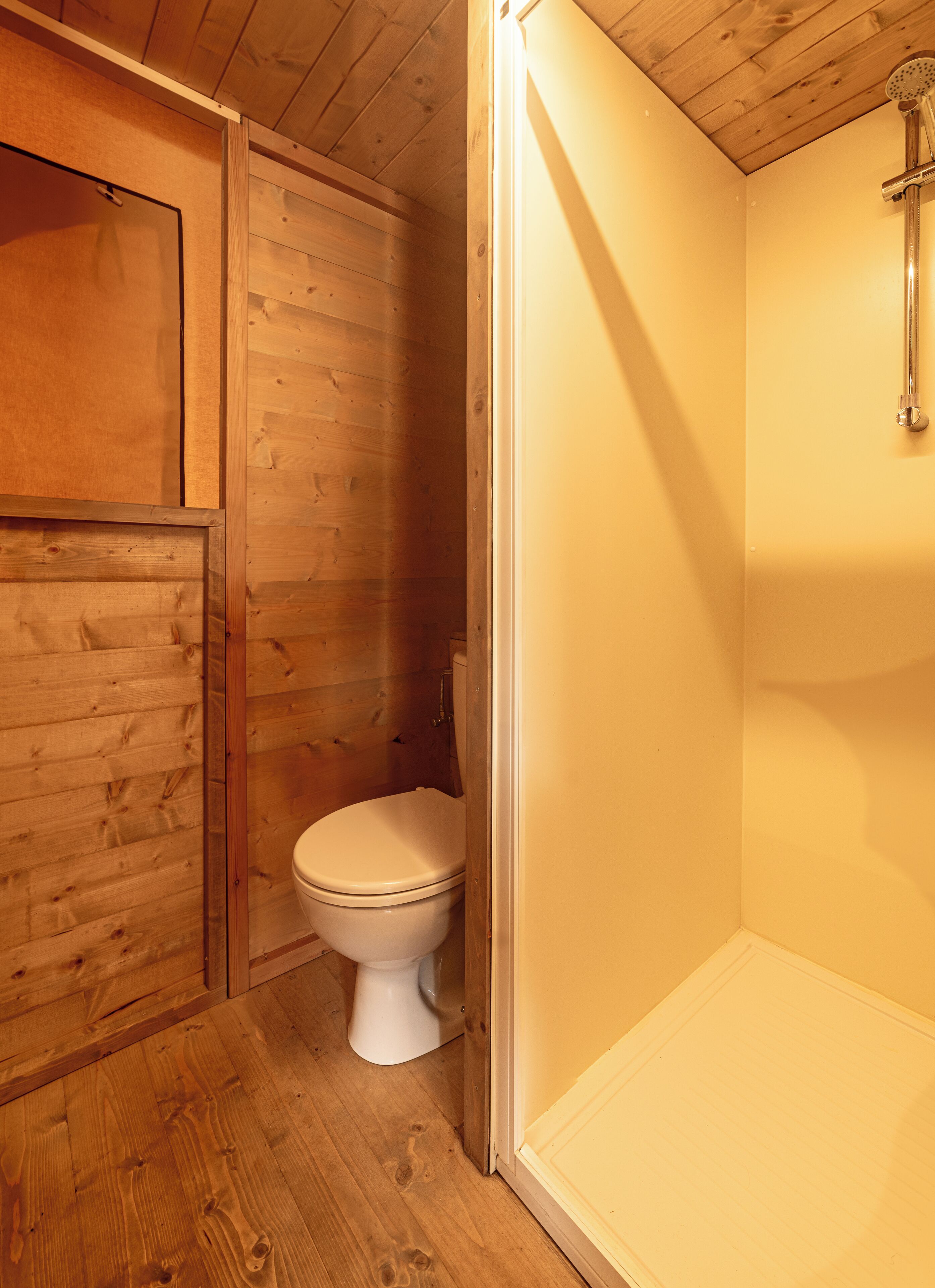 Un baño de madera con inodoro y ducha.