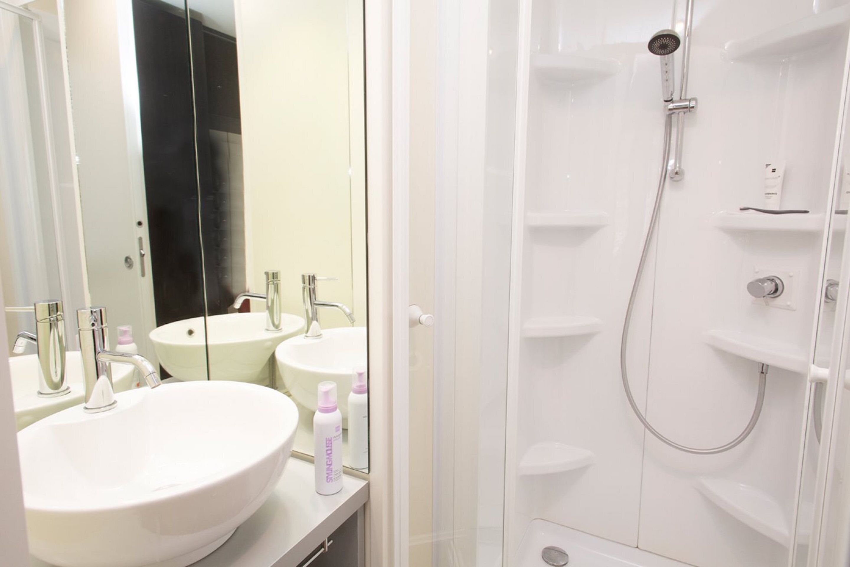 Un baño con dos lavamanos, un espejo y una zona de ducha.